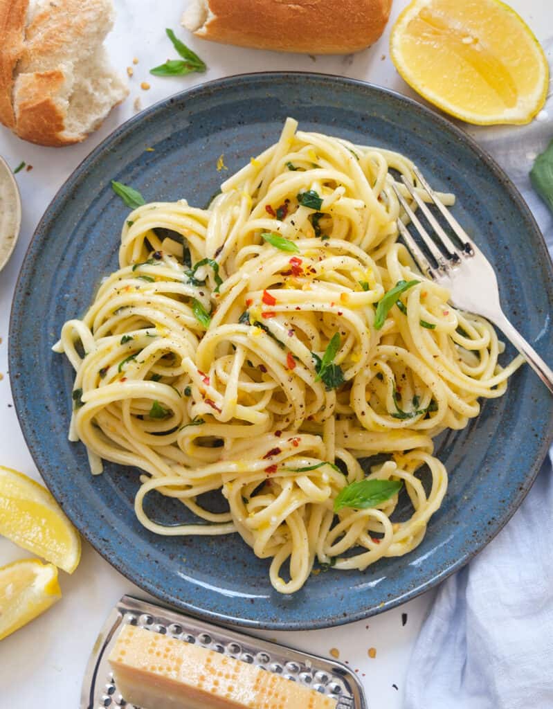 Top view of a serving of lemon garlic pasta on a blue plate.