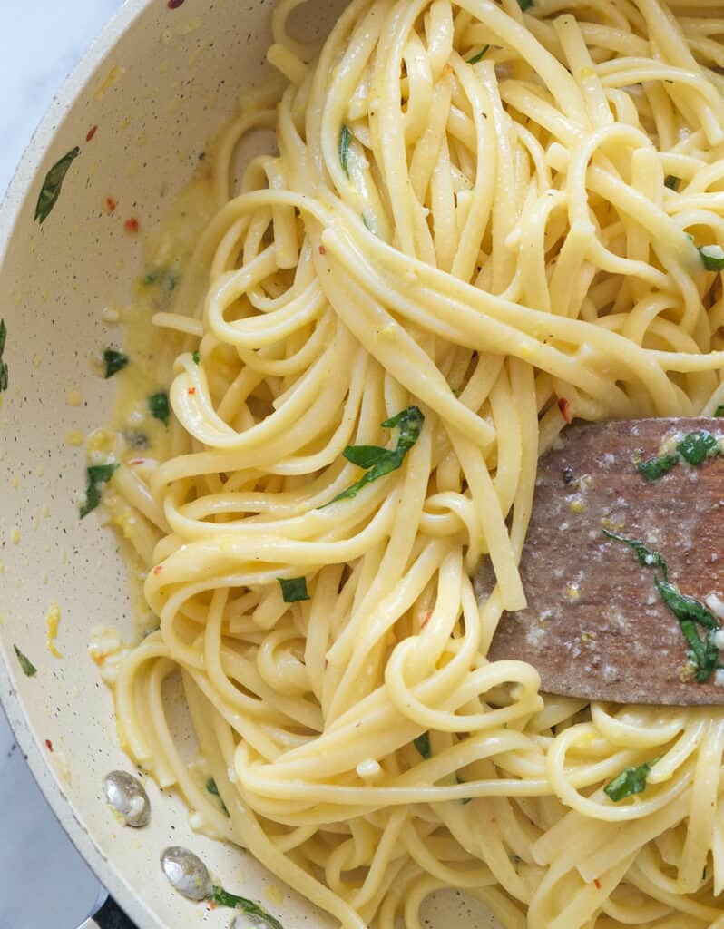 Close-up of juicy linguine pasta coated in lemon garlic butter sauce.