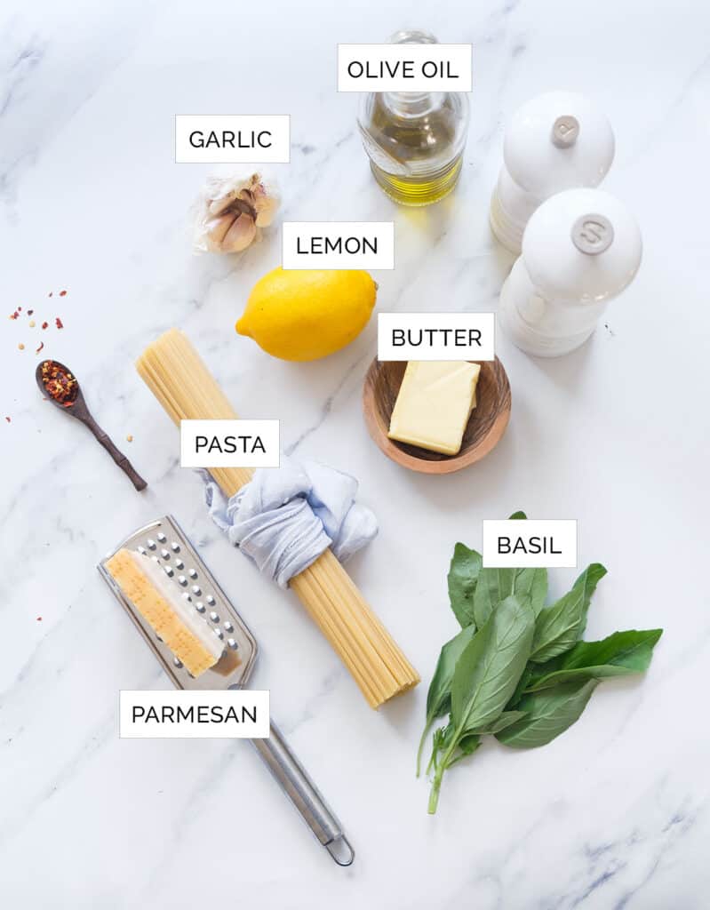 The ingredients to make this lemon garlic pasta are arranged over a white background.