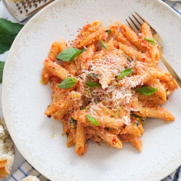 Top view of a white plate with a penne pasta recipe featuring tomato sauce and ricotta.