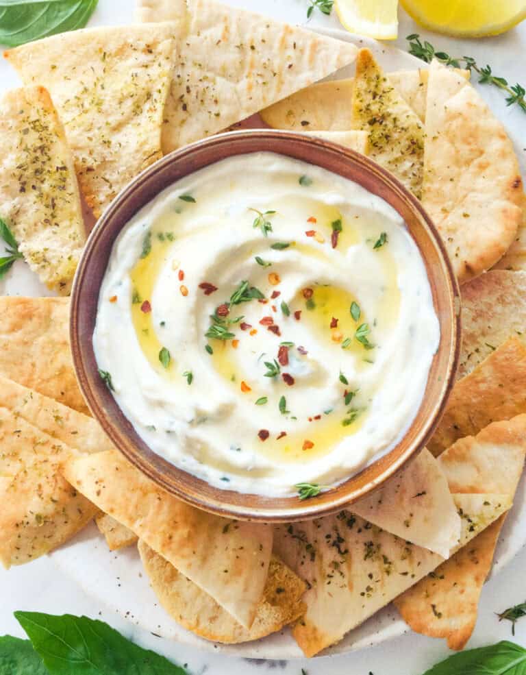 Top view of a bowl full of creamy and fluffy ricotta dip served with pita chips.