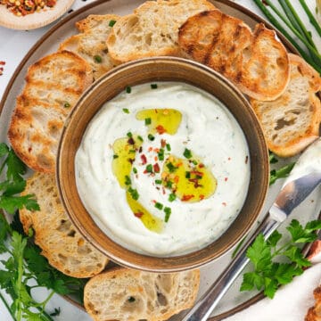 Top view of a small bowl with whipped ricotta served with crostini.