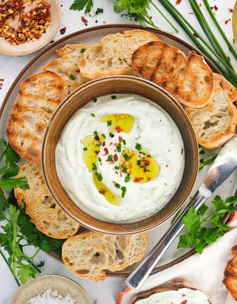 Top view of a small bowl full of whipped ricotta served with crostini.