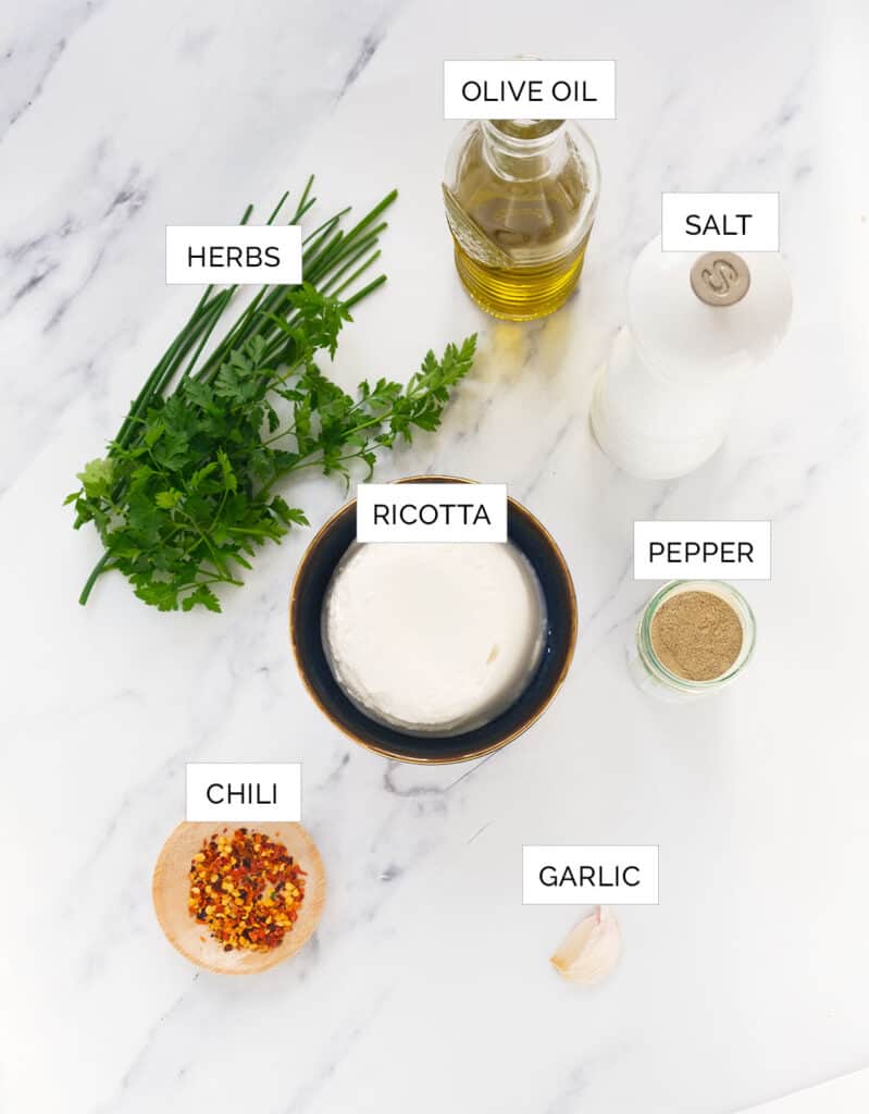 The ingredients to make this whipped ricotta are arranged over a white background.