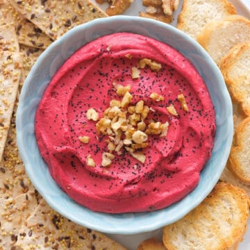 Top view of a light blue bowl full of creamy pink beet hummus.