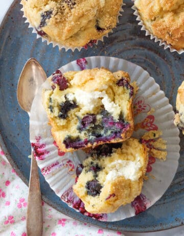 Top view of a blueberry cream cheese muffins slit into halves and served onto a blue plate.