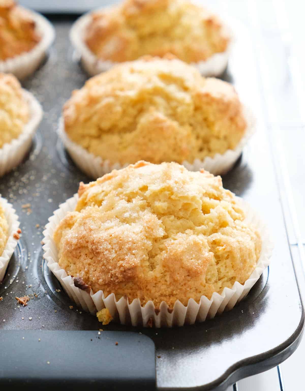 Close-up of a few freshly baked cream cheese muffins in a black muffin pan.