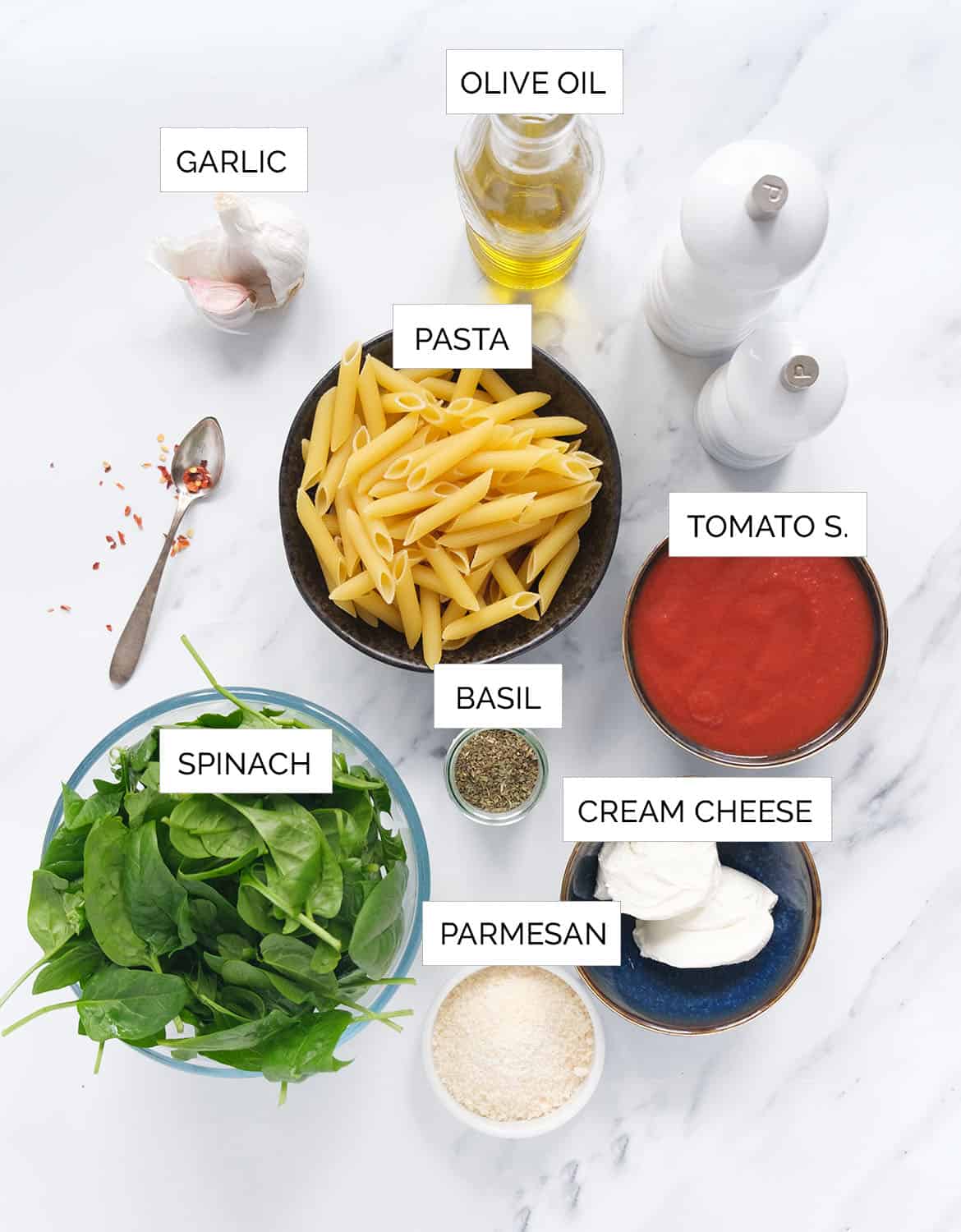 The ingredients to make this creamy tomato spinach pasta are arranged over a white background.
