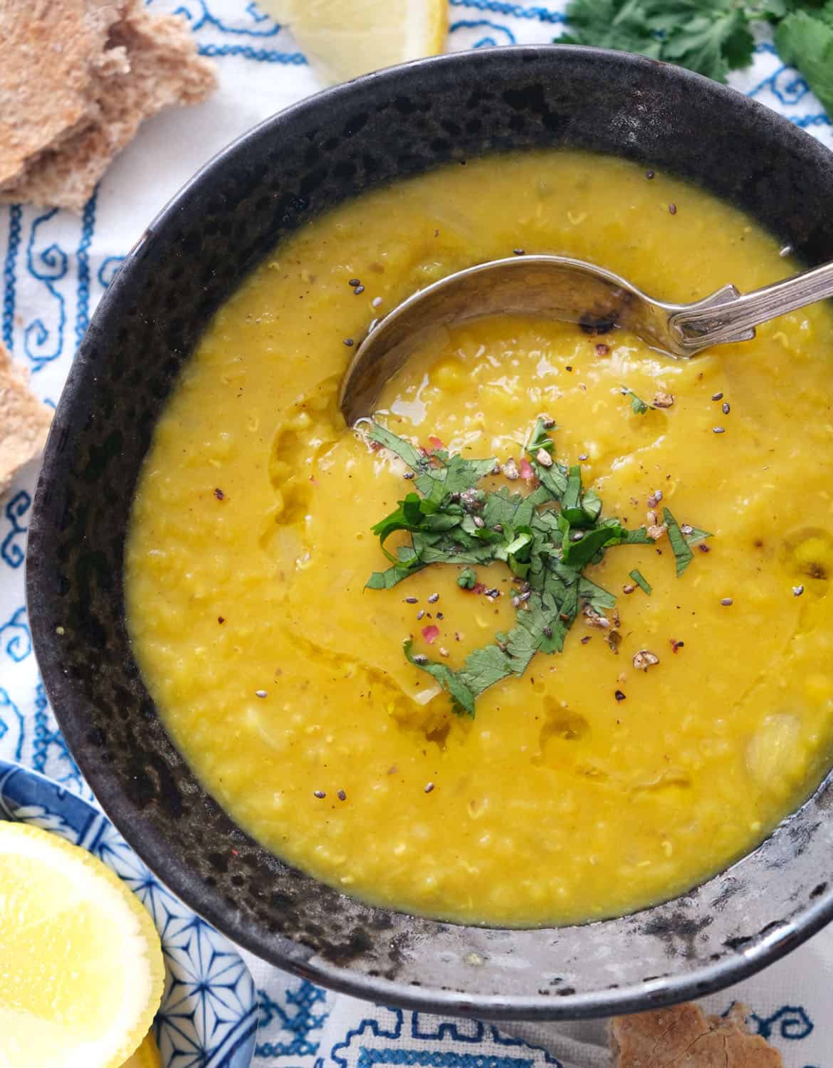 Top view of a black bowl full of Lebanese lentil soup garnished with coriander.