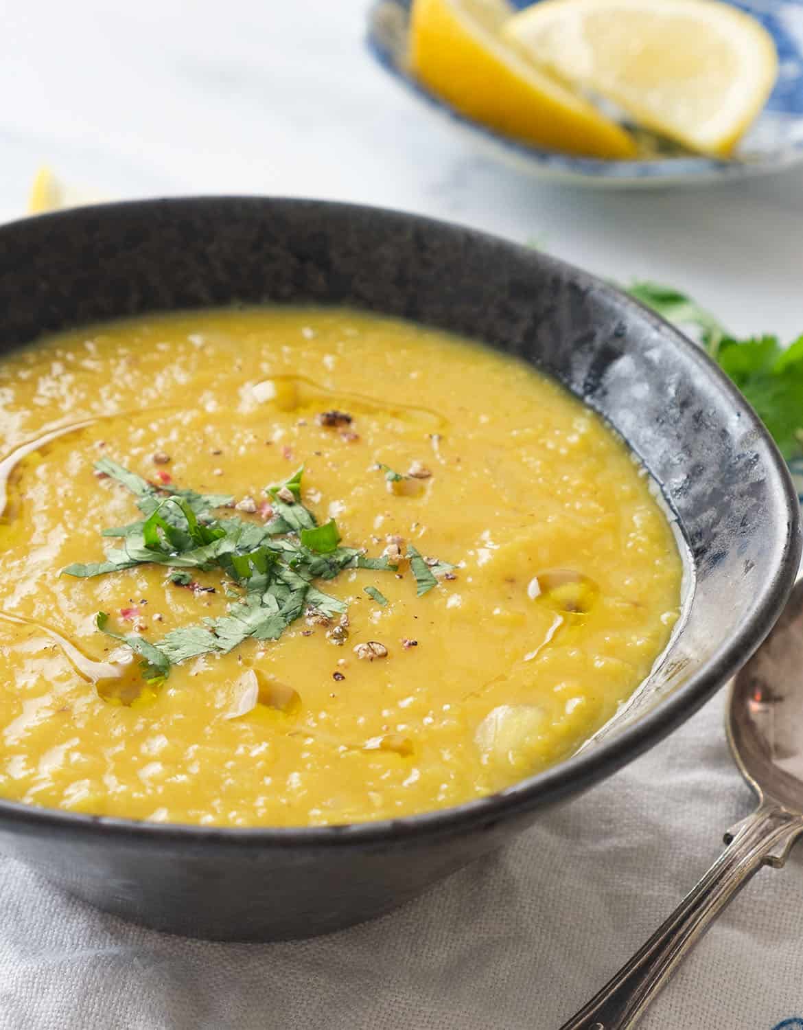 Close-up of a black bowl full of creamy, golden Lebanese lentil soup.