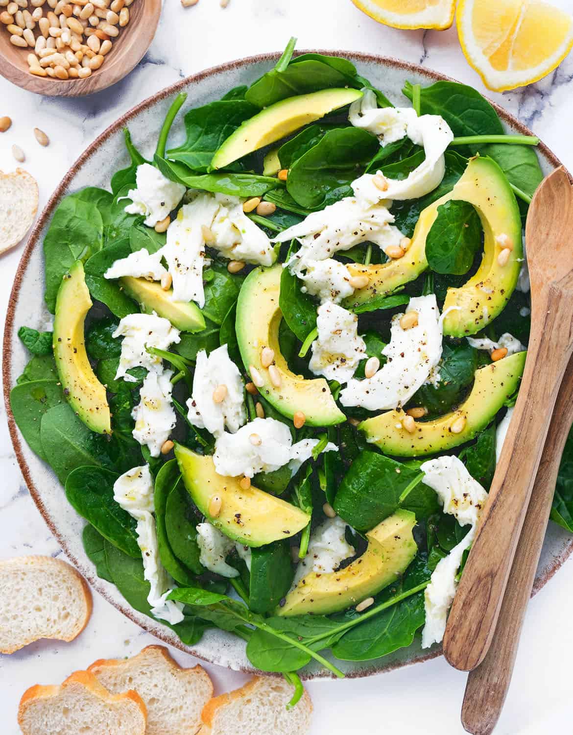 Top view of a serving plate full of spinach avocado salad with mozzarella.