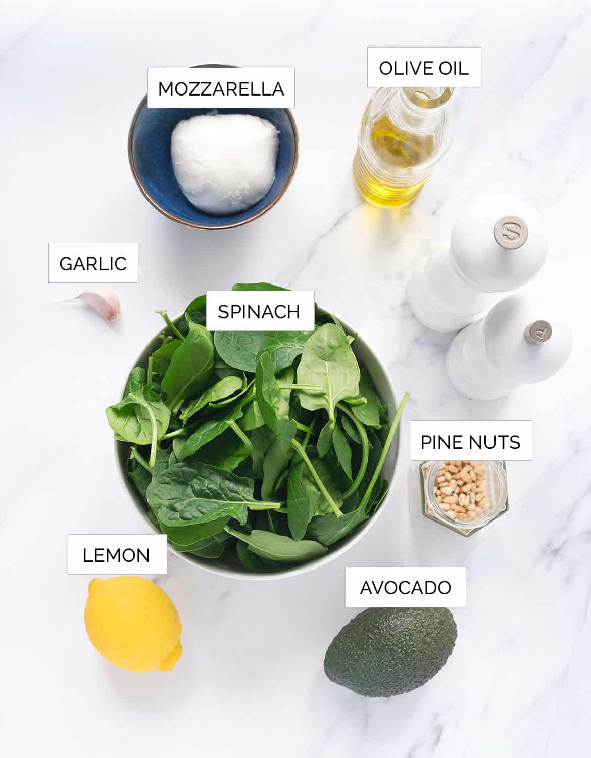 The ingredients to make this spinach avocado salad with fresh mozzarella are arranged over a white background.