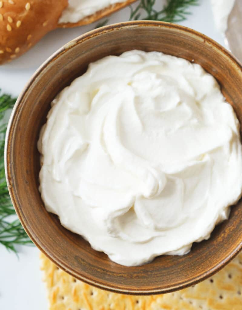 Close-up of a brown bowl full of whipped cream cheese showing its fluffy texture.