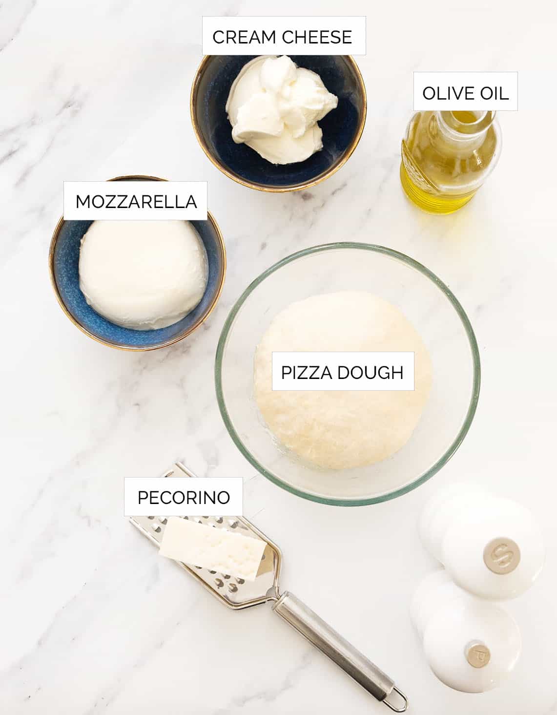 Top view of the ingredients to make cream cheese pizza arranged over a white background.