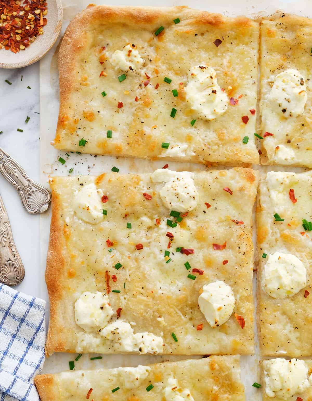 Top view of a large cream cheese pizza cut into slices.