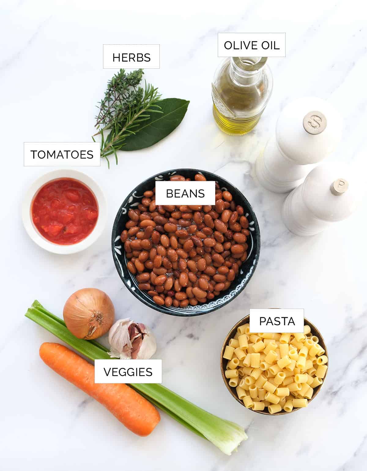 Top view of the ingredients to make pasta fazool over a white background.