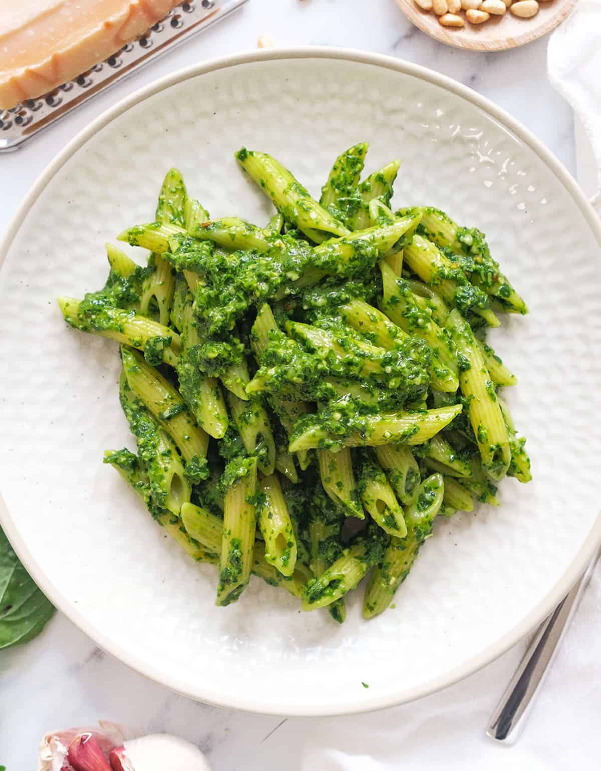 Top view of a white plate full of spinach pesto pasta.