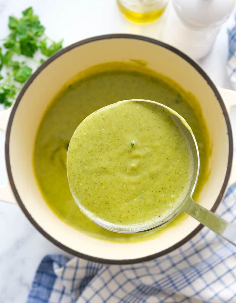 Close-up of a ladle full of creamy vegan broccoli soup. 