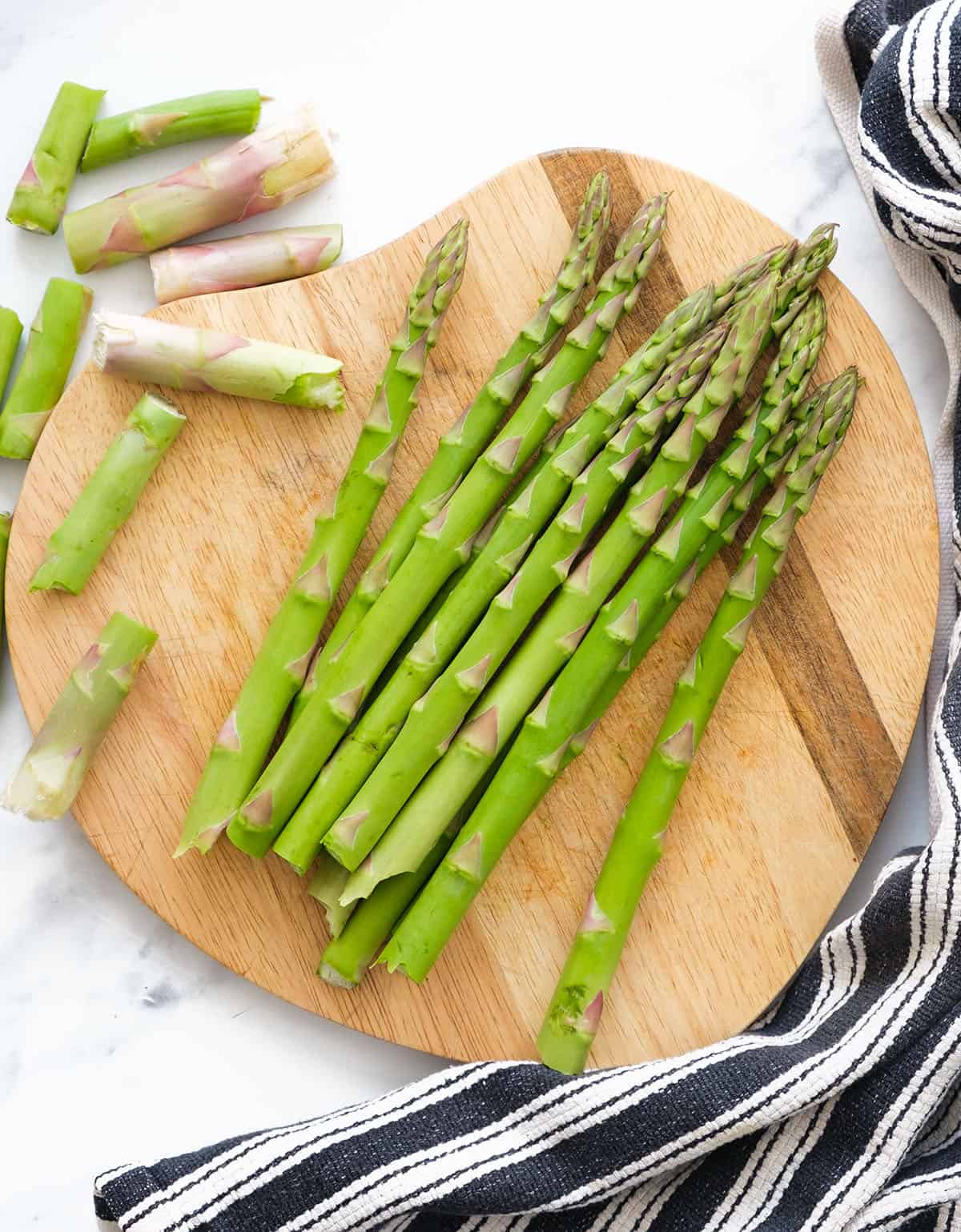 Top view of a bunch of fresh asparagus on a wooden chopping board.