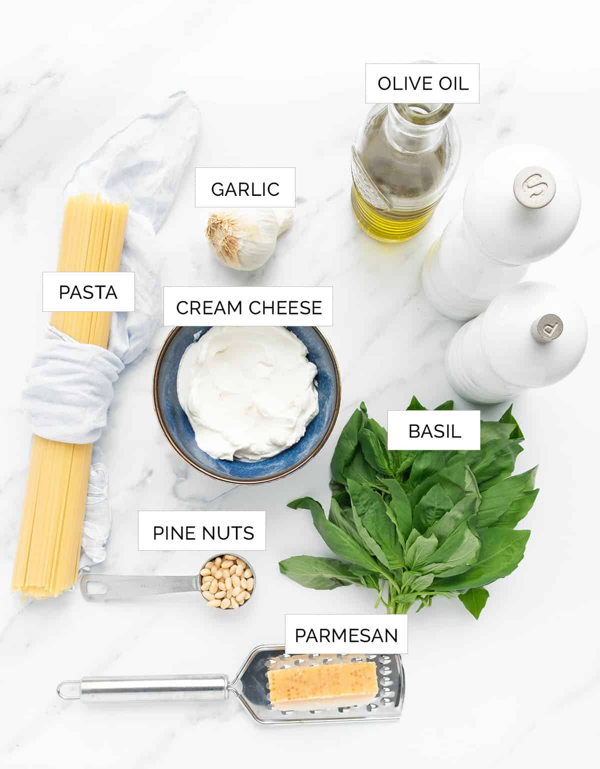 Top view of the ingredients to make creamy pesto pasta over a white background.