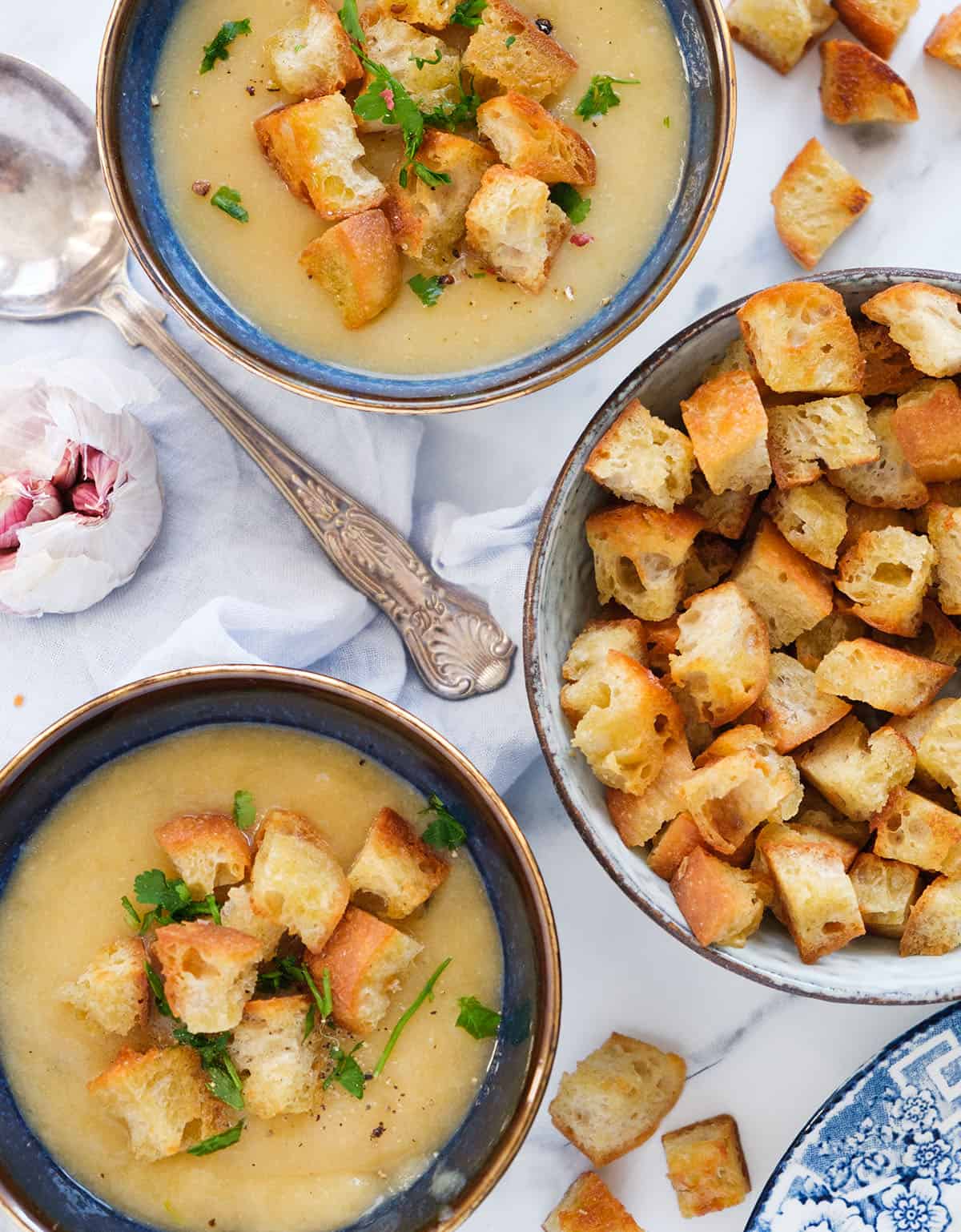 Top view of two bowls of soup served with crispy croutons.
