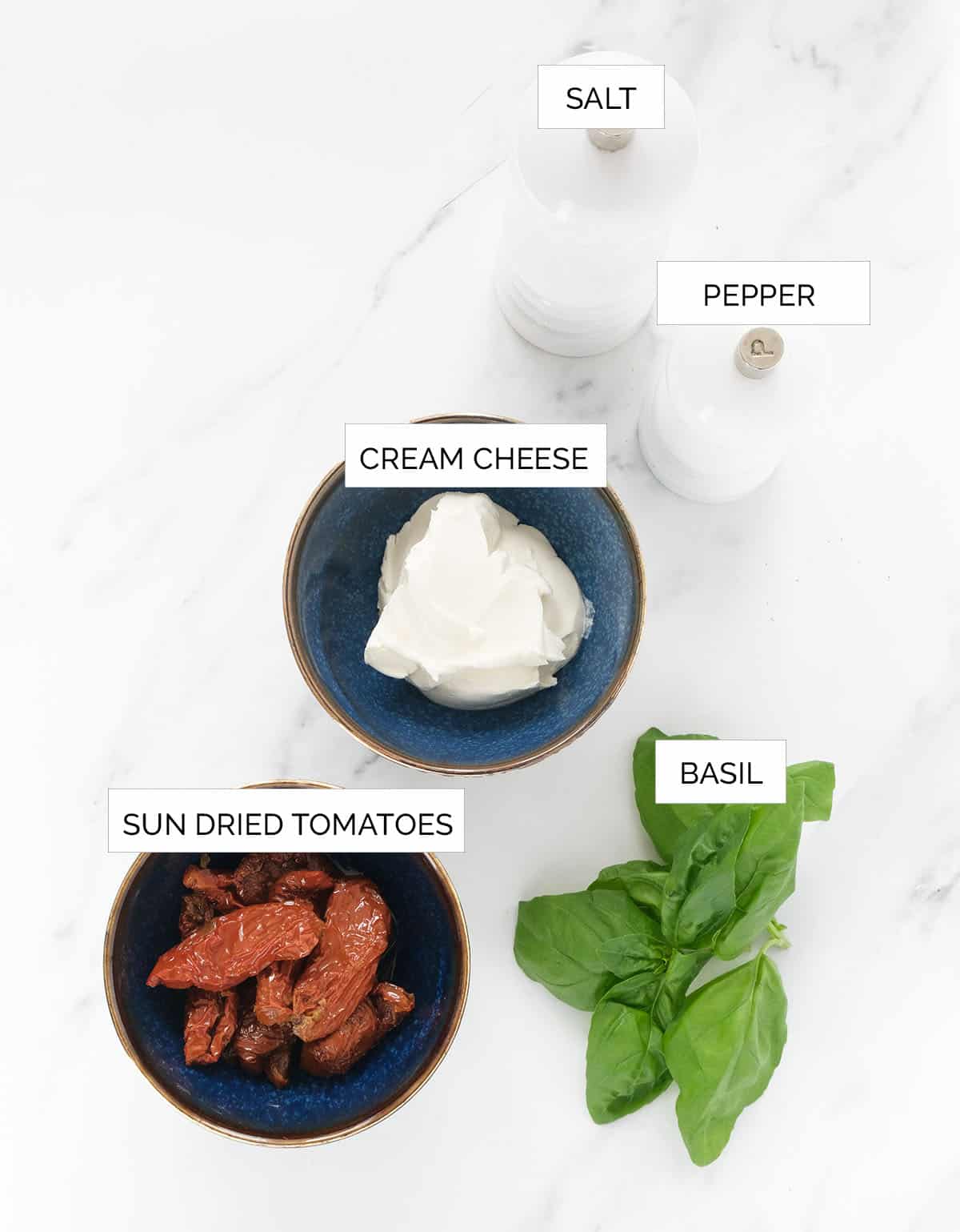 The ingredients to make this sun dried tomato cream cheese are arrange over a white background.