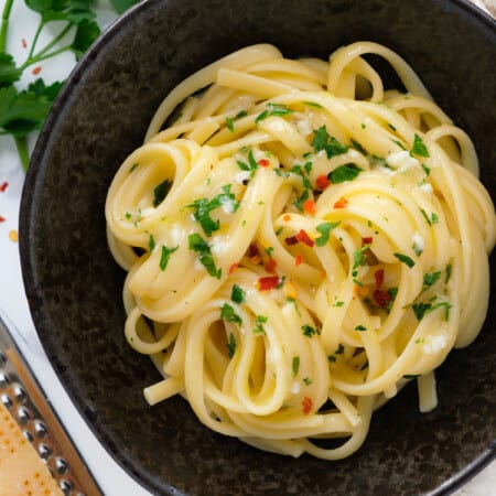 Top view of a black bowl full of luscious white wine pasta.