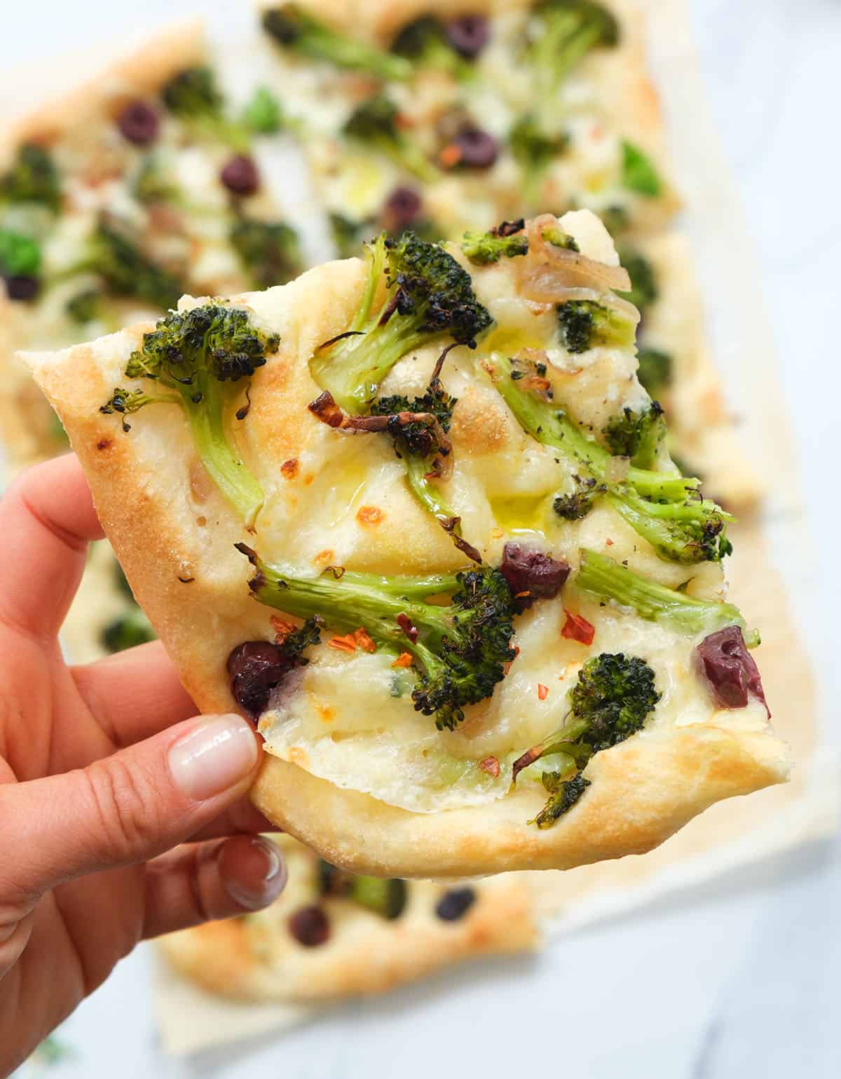 Close-up of a few slices of broccoli pizza over a white background.