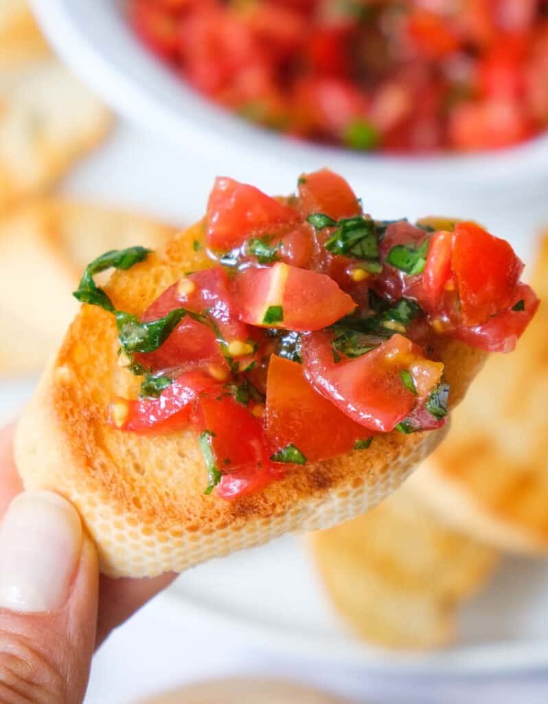 Close-up of a slice of bread topped with tomato bruschetta dip.