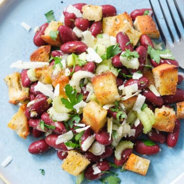 Top view of a blue plate with kidney bean salad with croutons.