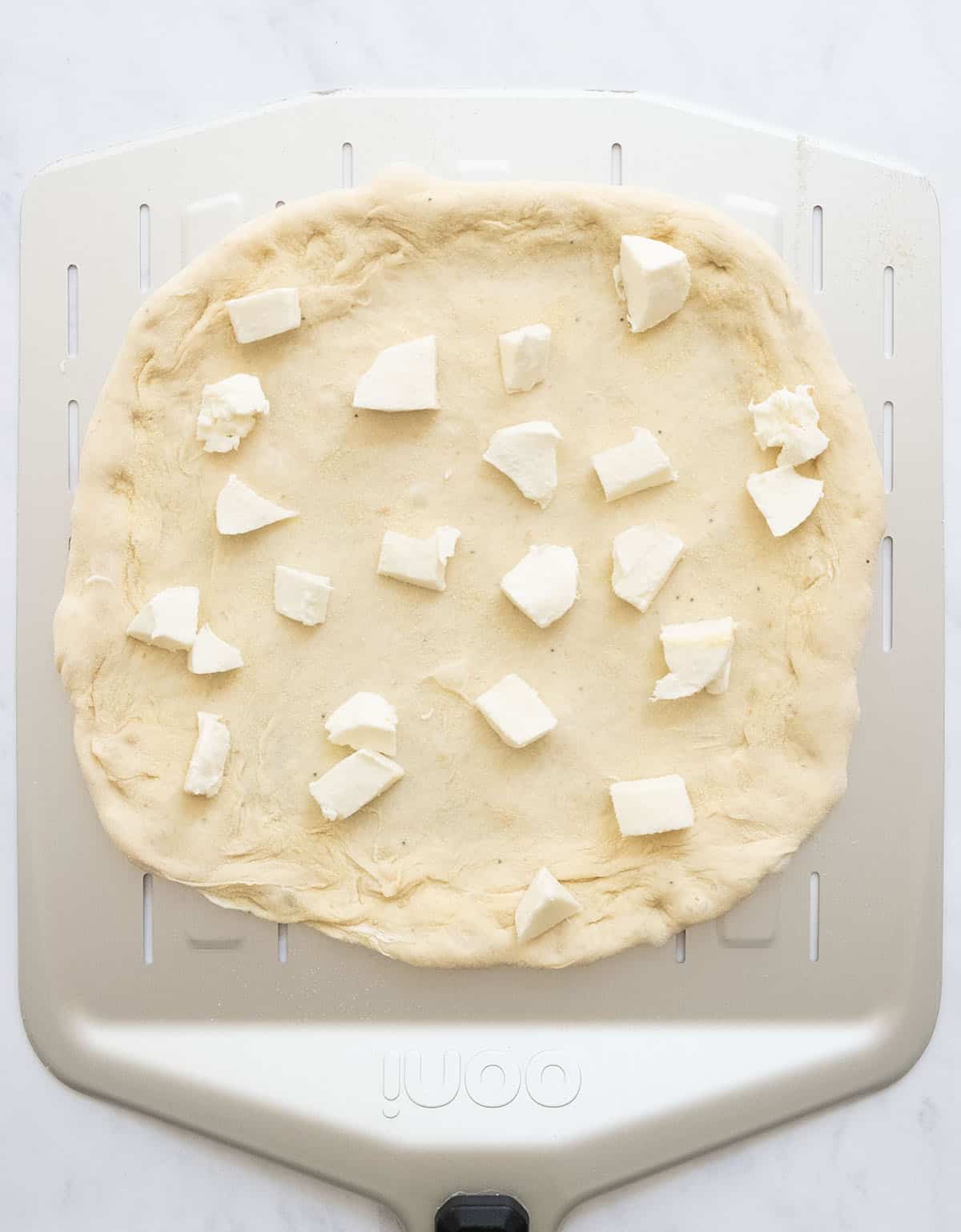 Top view of a round pizza with mozzarella only just before baking.