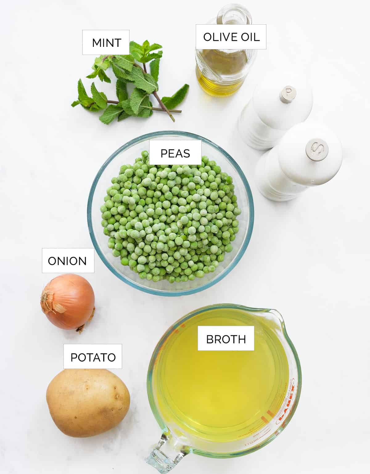 Top view of the ingredients to make this green pea soup arranged over a white background.