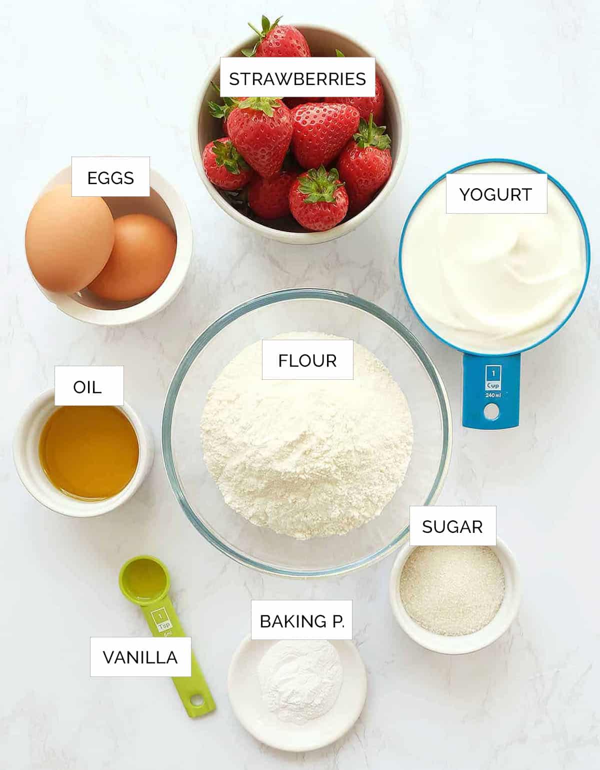 The ingredients for this strawberry bread are arranged on a white marble surface.