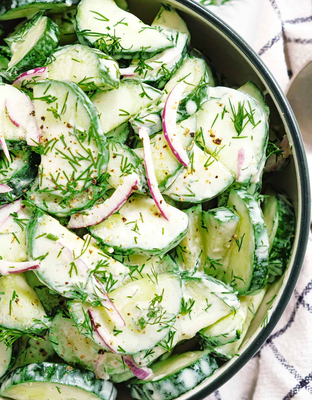 Top view of a bowl full of cucumber dill salad coated with a lemon yogurt dressing.