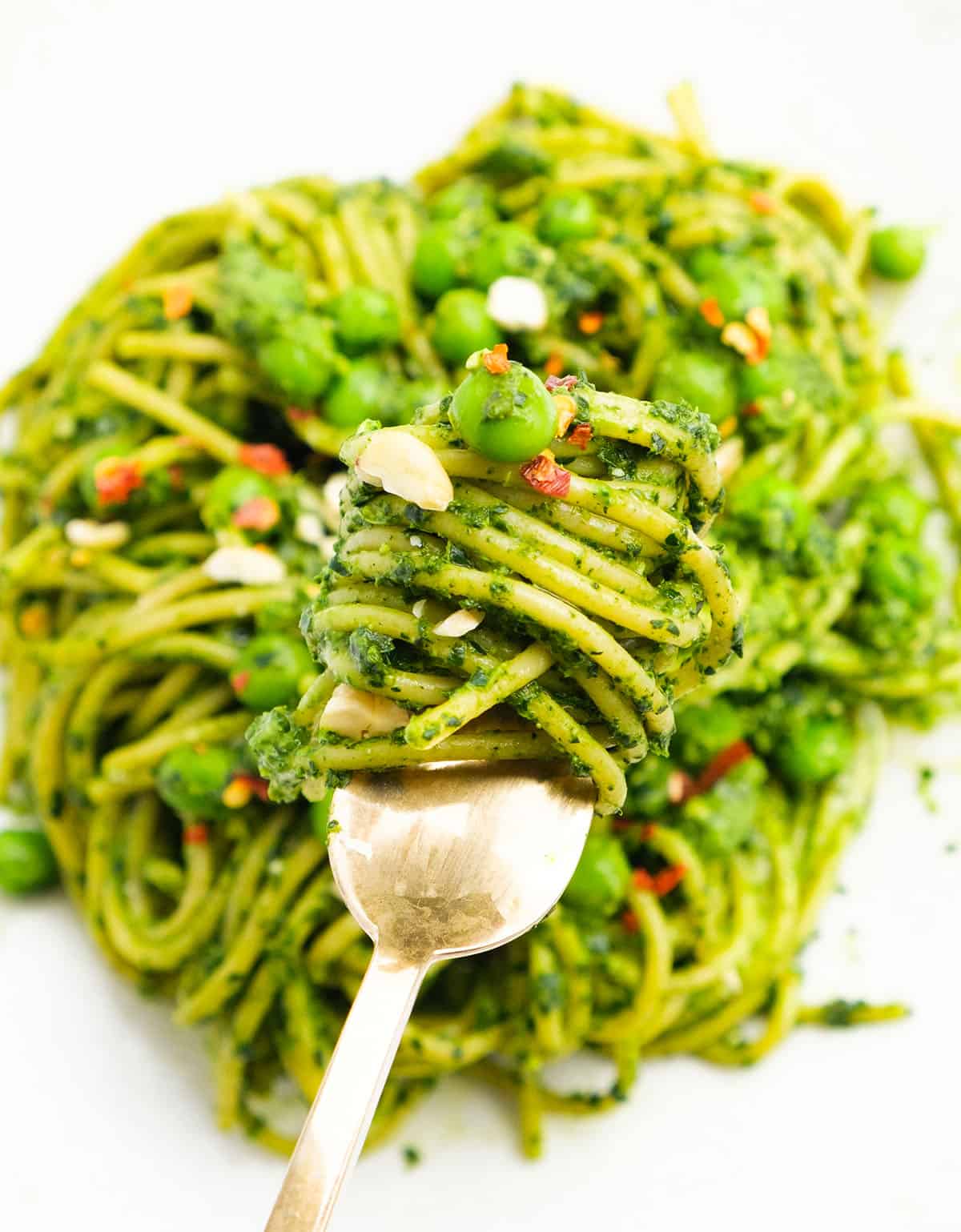 Close-up of a fork full of healthy spaghetti coated with green pesto.