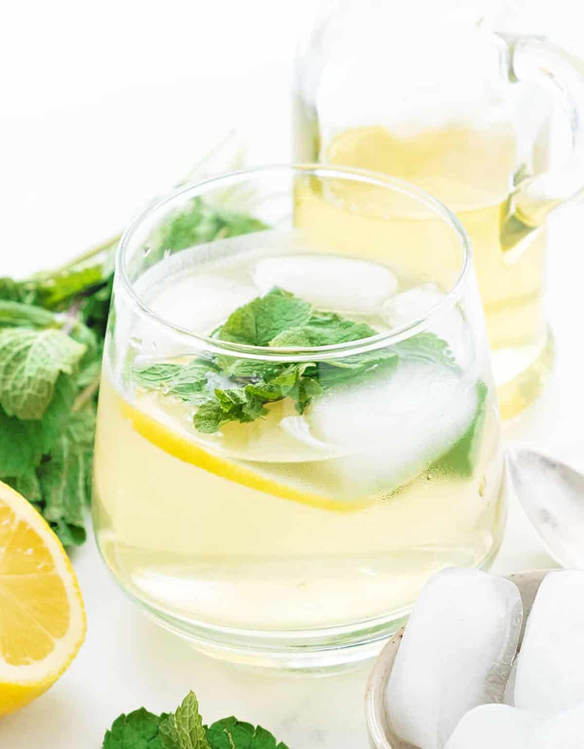 Close-up of a glass full of mint syrup with ice and mint leaves.