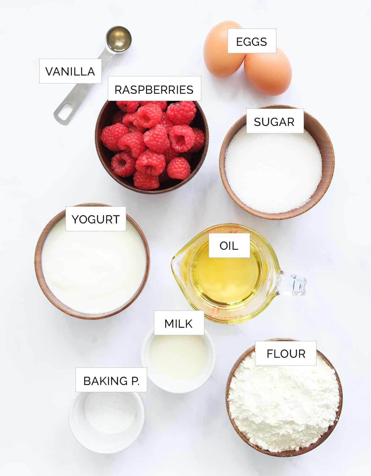 Top view of the ingredients to make raspberry muffins arranged over a white background.