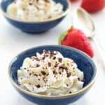 Two small blue bowls full of ricotta cream garnished with chocolate chips.