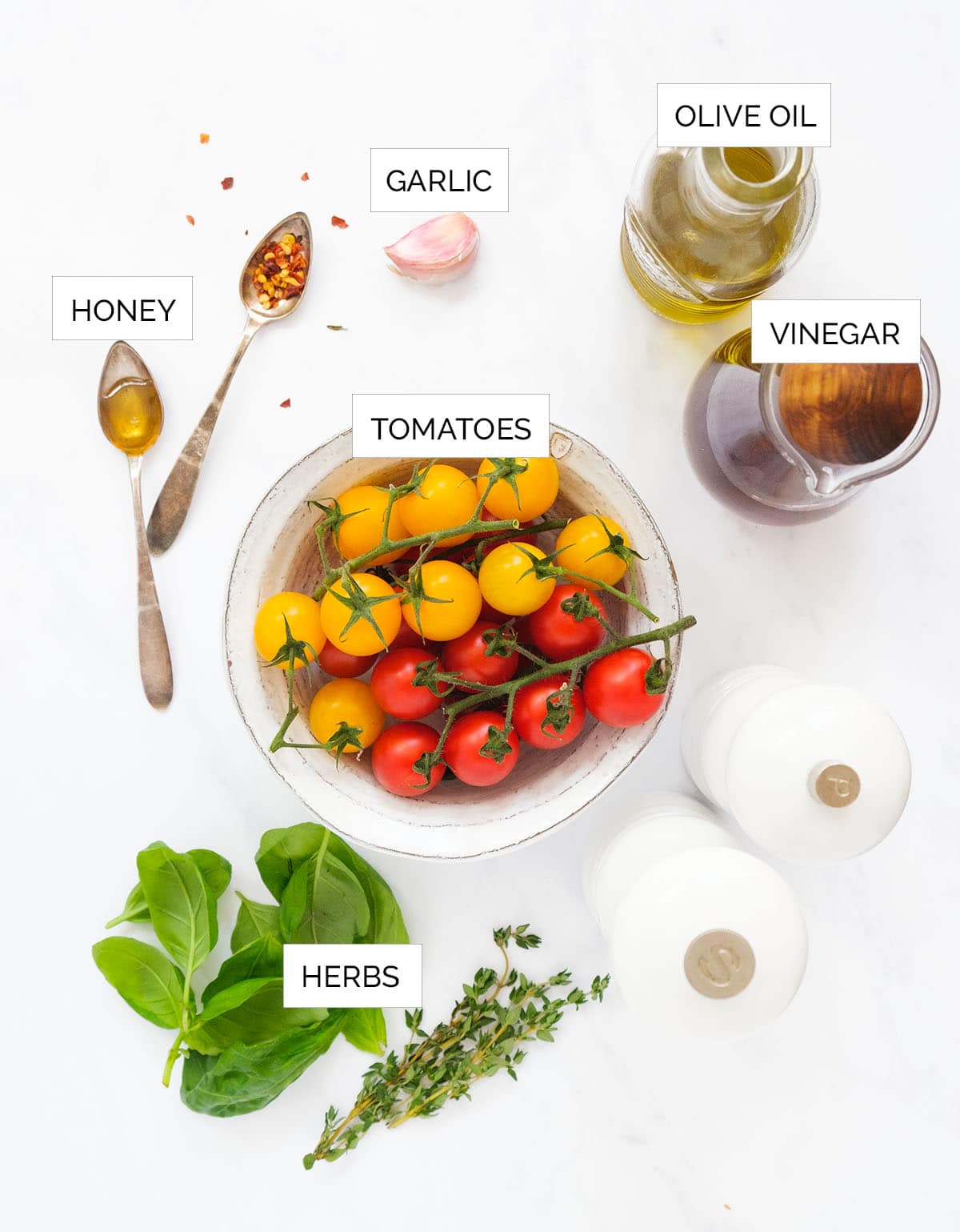 Top view of the ingredients to make marinated cherry tomatoes over a white background.