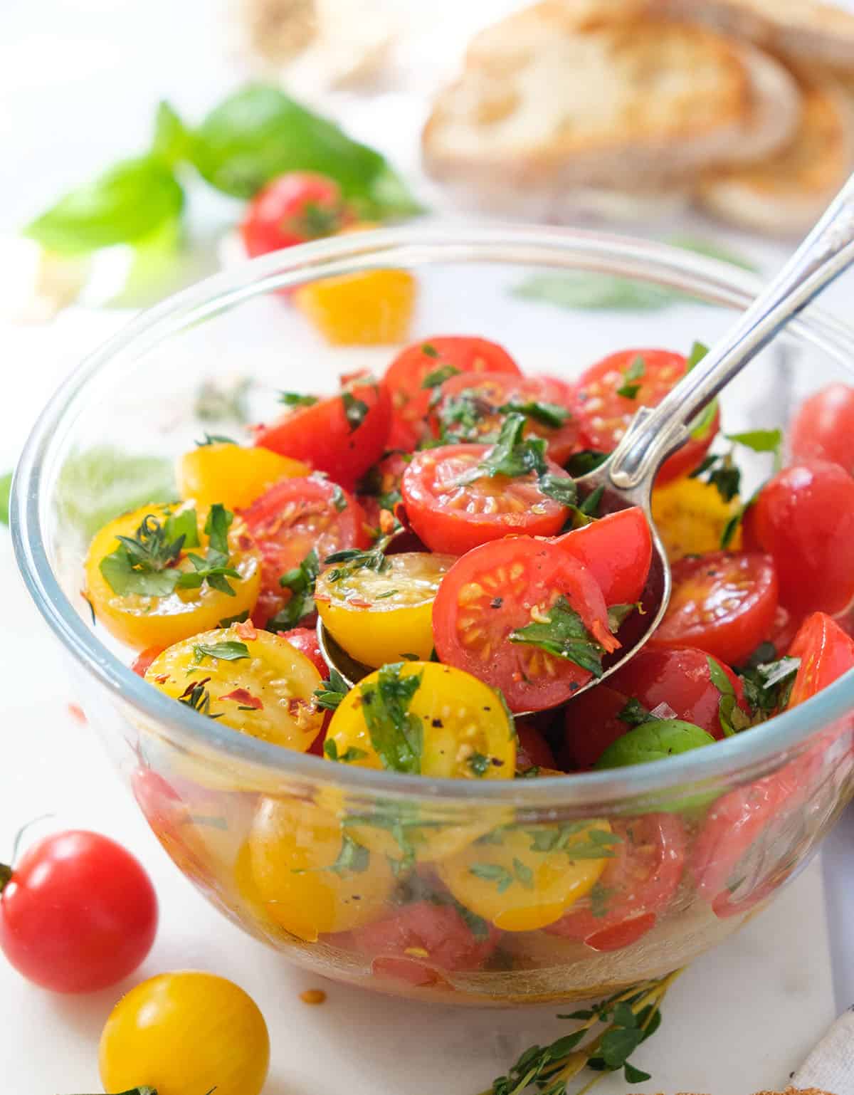 Close-up of a glass bowl full of red and yellow marinated cherry tomatoes.