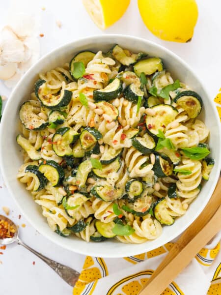 Top view of a white salad bowl with zucchini pasta salad.