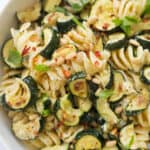 Close-up of a white bowl full of zucchini pasta salad.