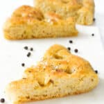 Close-up of a few slices of black pepper focaccia over a white background.