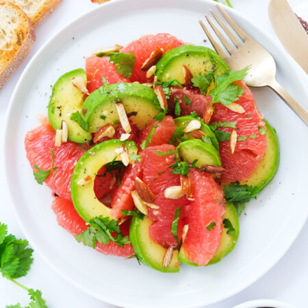 Top view of a white plate full of grapefruit salad with avocado.