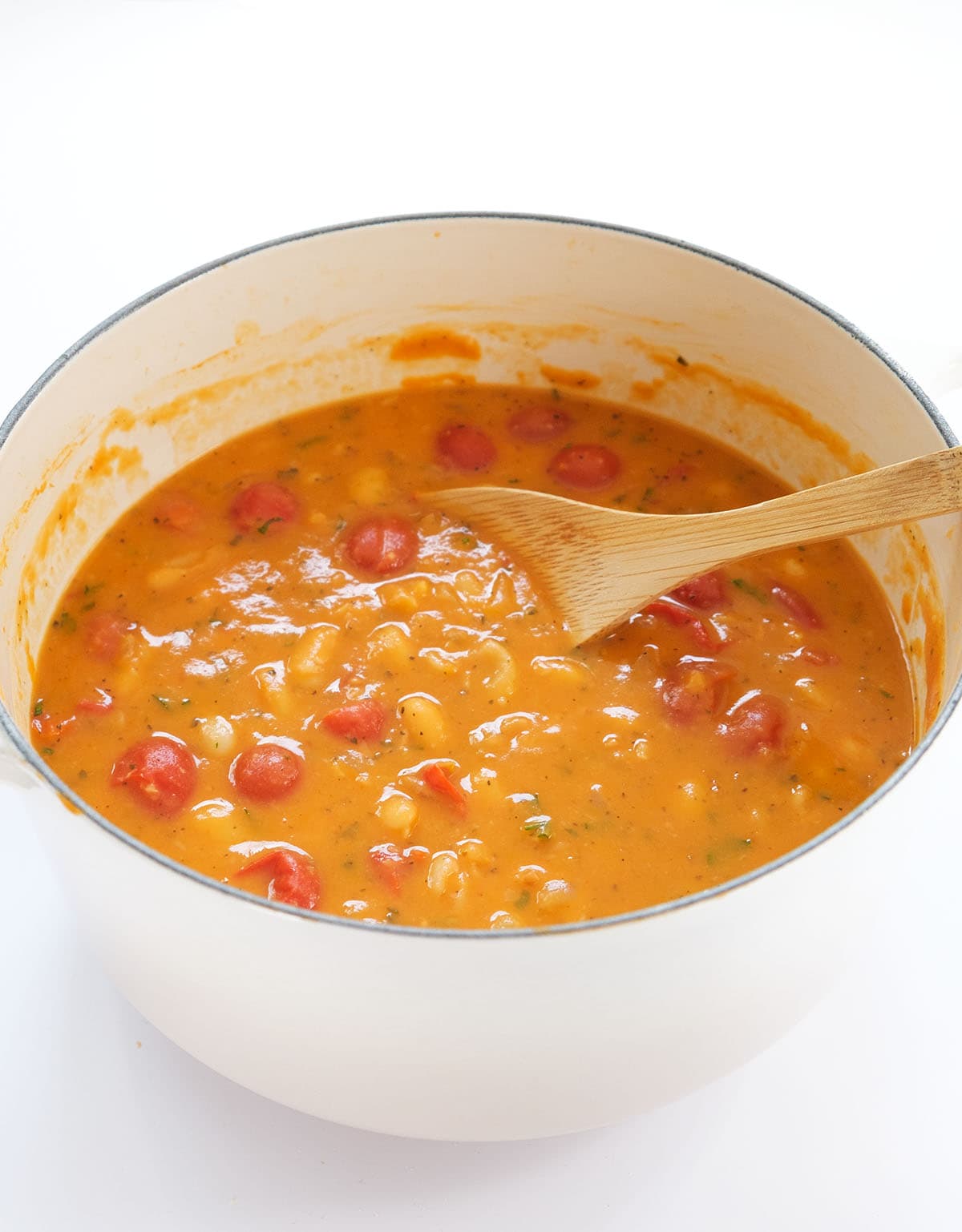 A white Dutch oven full of creamy white bean soup.