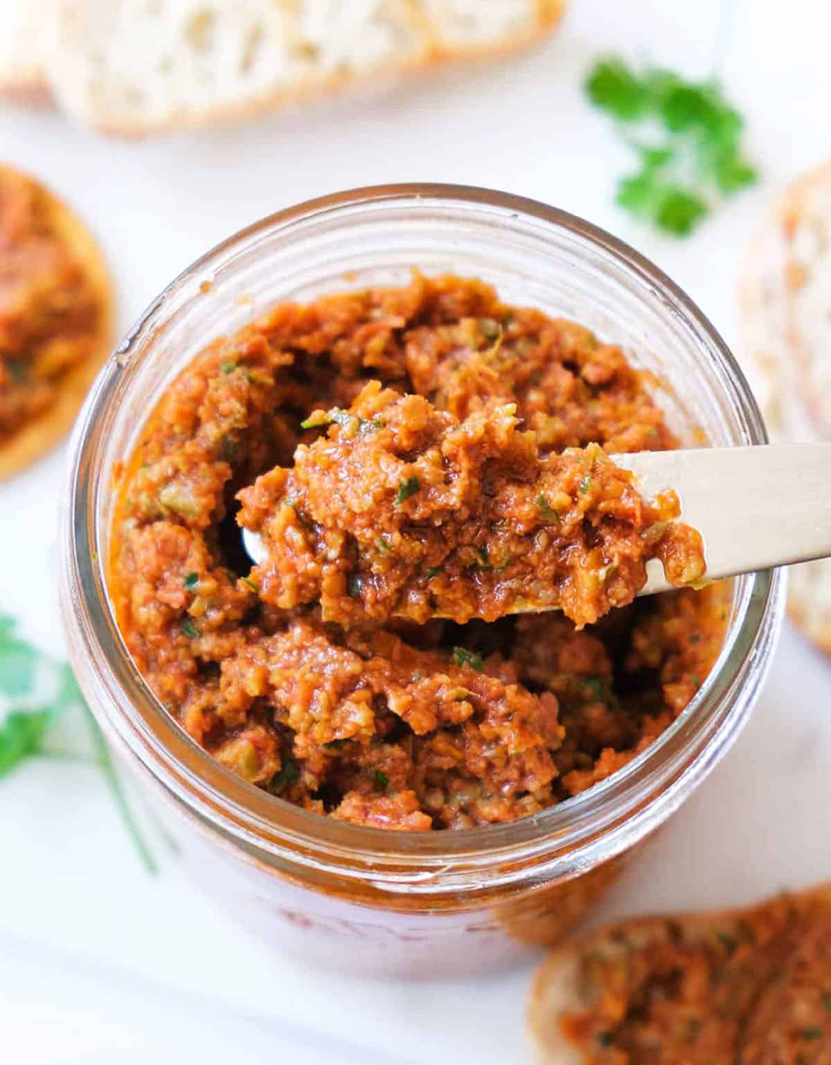 Close-up of one of the quickest sun-dried tomatoes recipes featuring a glass jar full of sun dried tomato spread.