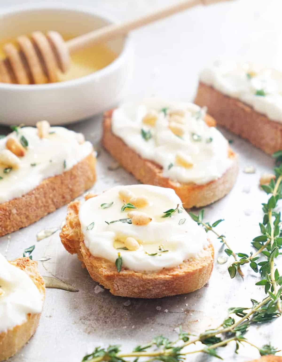 Close-up of an easy ricotta recipe featuring crostini topped with whipped ricotta, pine nuts and honey.