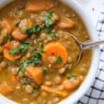 Close-up of a white bowl full of carrot lentil soup.