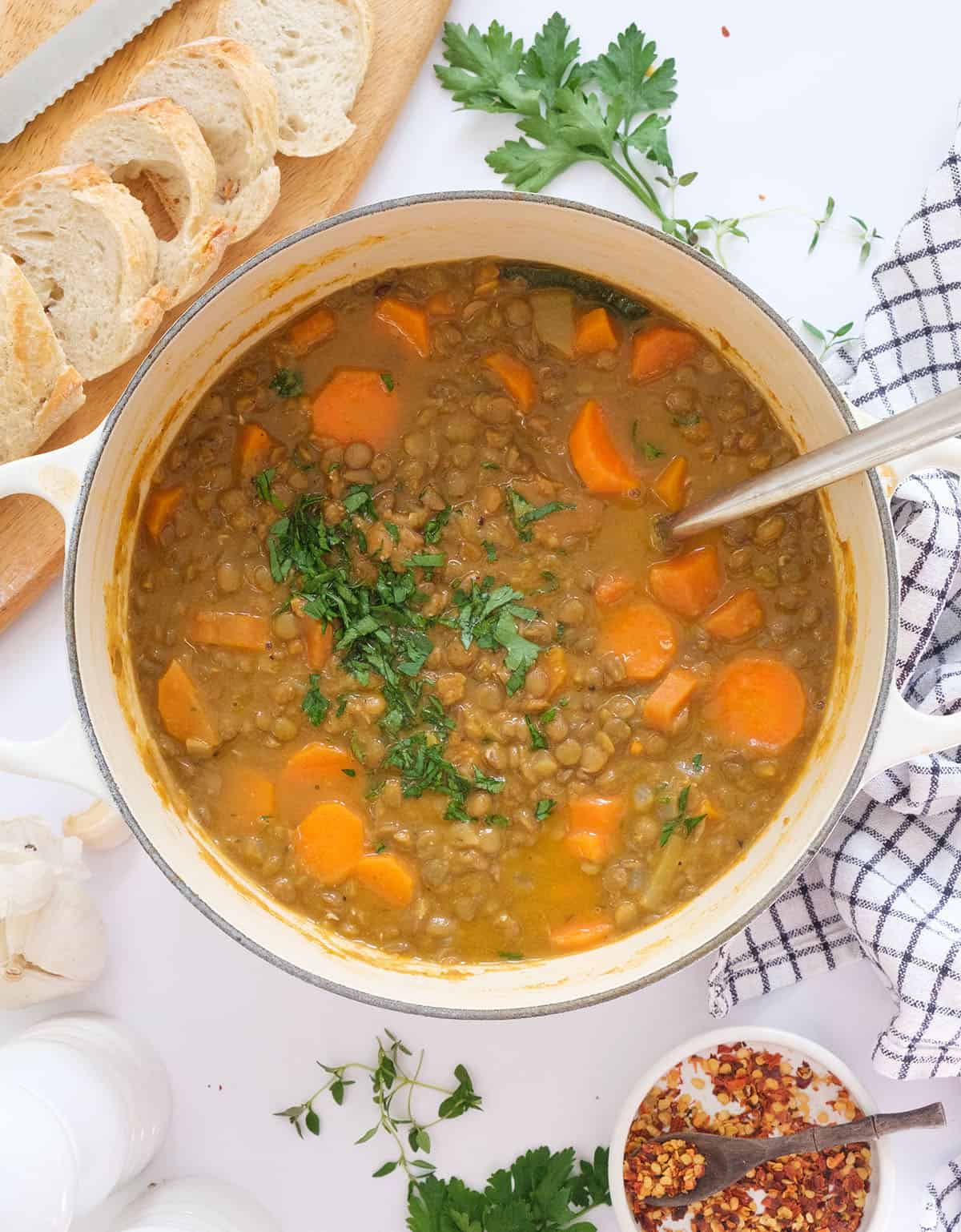 Top view of a white Dutch oven full of carrot lentil soup over a white background.