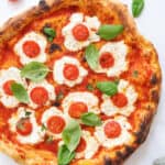 Top view of a ricotta pizza with cherry tomatoes and basil.